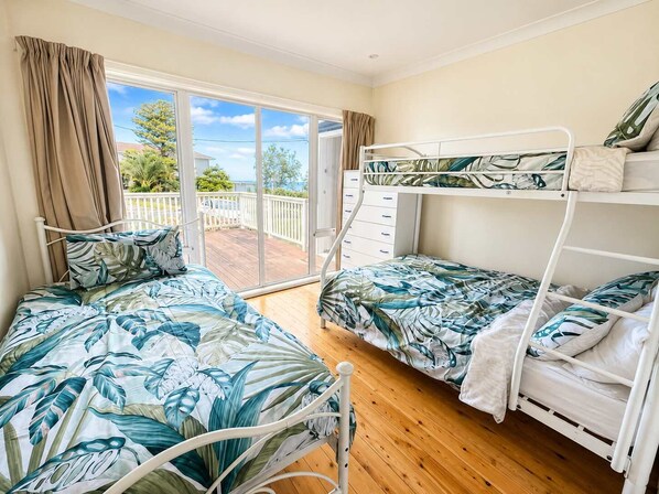 A room with two bunk beds, a sliding glass door leading to a balcony, and a wooden floor.
