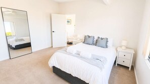 Une chambre à coucher avec un lit, une table de chevet, un miroir et une porte.