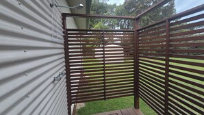 Un espace extérieur abrité, doté d’un toit en métal, d’une terrasse en bois et d’une clôture en métal.