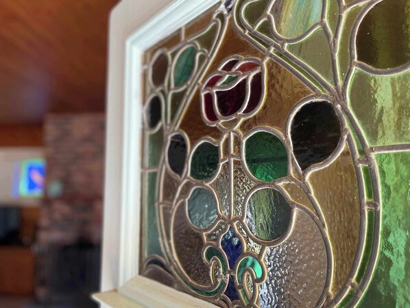 Ein Detailaufnahme eines Buntglasfensters mit filigranen Mustern und einem Holzrahmen.