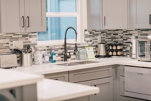 A modern kitchen with a white countertop, stainless steel appliances, and a backsplash with multicolored tiles.