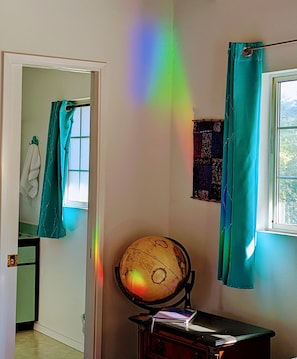 A room with a globe on a desk, teal curtains, and a window with a view. - Luxurious, Private Suite (Hilo)