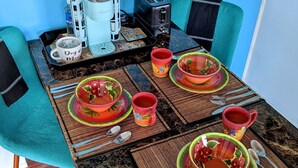 A dining table set with colorful bowls and cups, a coffee maker, and a toaster. - Luxurious, Private Suite (Hilo)