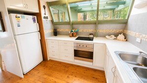 Une cuisine de taille réduite équipée d’un réfrigérateur, d’une cuisinière et d’un évier.