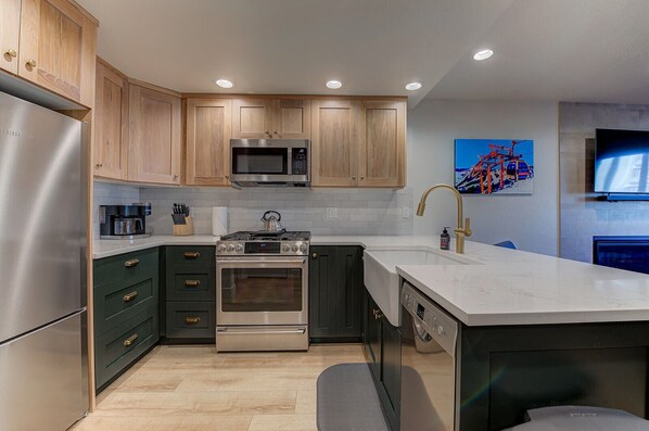A modern kitchen with stainless steel appliances, wooden cabinets, and a large island with a sink. - Park Ave Townhome - Walk to Main St. (Park City)