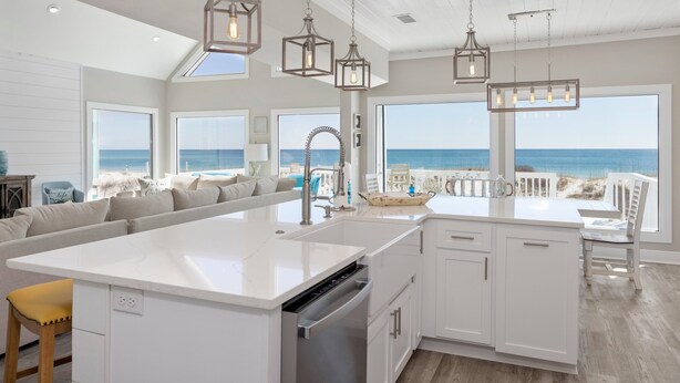 A spacious kitchen with a large island, white cabinetry, and a view of the beach. - Modern Beach Front Home with Volleyball net | Summer's Point by Kaiser Vacation Rentals. (Gulf Shores)