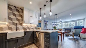 Una cocina moderna con una isla central, armarios empotrados e iluminación colgante.