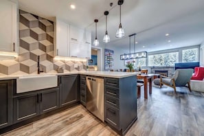 A modern kitchen with a central island, built-in cabinets, and pendant lighting.
