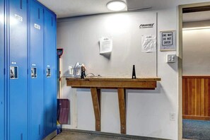 A locker room with blue lockers numbered 412 and 413, a wooden table with various items, and a 'PROFILE' sign on the wall. - Greystone Lodge 329 Ski-in/Out by Acer Vacations (Whistler)