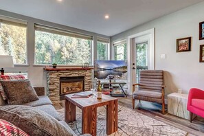 Ein Wohnzimmer mit Kamin aus Stein, einer Couch, einem Couchtisch und einem Fernseher.