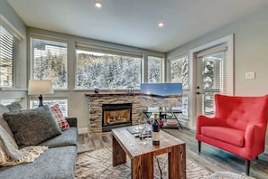 A living room with a fireplace, a sofa, a red armchair, and a television.