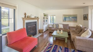 A living room with a fireplace, a red sofa, a green coffee table, and a beige sofa.