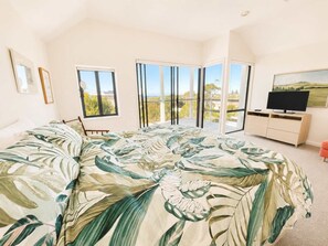 A bedroom with a large bed, a TV, and a balcony with a view. - The Bawley Hideaway - Modern Bawley Point hideaway near beach (Bawley Point)