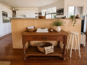A wooden kitchen island with a woven basket, a welcome note, and a candle. - The Bawley Hideaway - Modern Bawley Point hideaway near beach (Bawley Point)