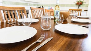 Mesa de comedor dispuesta con platos blancos, cubiertos y copas de vidrio, con una botella de vino SILOS sobre la mesa.