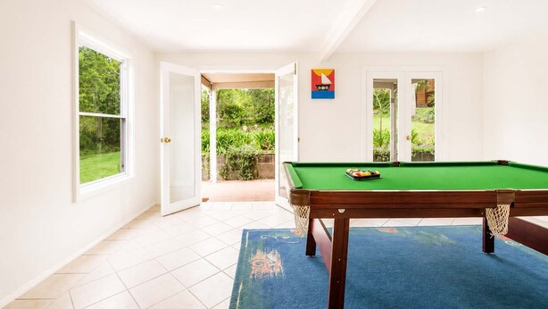 Una habitación con mesa de billar, una puerta que da a un jardín y vistas a zonas verdes.