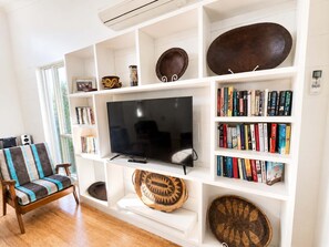 A living room with a flat-screen TV, bookshelves, a sofa, and decorative items.