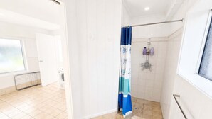 Un baño con ducha, inodoro y ventana.