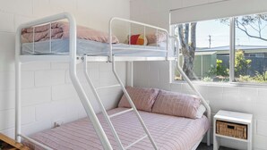A bunk bed with a window view, a bedside table, and a power outlet. - Retro Beach House at Mollymook (Mollymook)