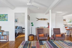 Amplia sala de estar con una decoración de peces grande, una estantería y un comedor con una cocina al fondo.