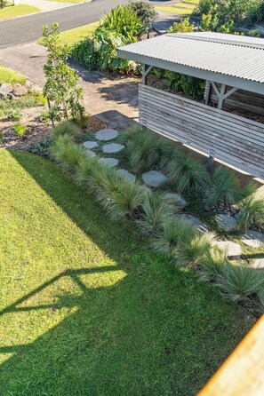 Un jardín ajardinado con un sendero que lleva a un edificio de techo inclinado.