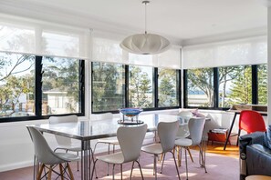 Ein moderner Essbereich mit einem Glastisch, weißen Stühlen und einer farbenfrohen Glasschale als Mittelpunkt.