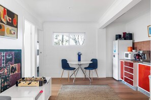 A modern kitchen with a dining area, a foosball table, and a view of trees through the window.