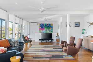 A spacious living room with a large TV, modern furniture, and a colorful abstract painting.