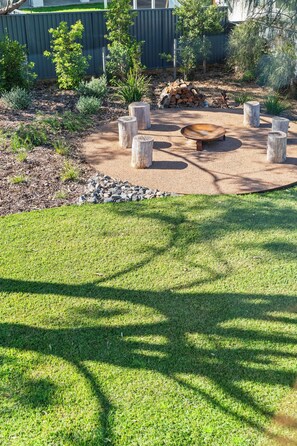 A well-maintained outdoor area with a circular seating arrangement, surrounded by a grassy lawn and a wooden fence.