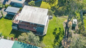 A two-story building with a flat roof, surrounded by a well-maintained lawn and trees. - Retro Beach House at Mollymook (Mollymook)