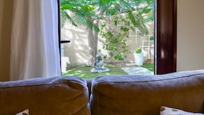 Vista dalla finestra su un giardino con una statua di Buddha, un recinto bianco e piante in vaso.