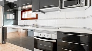 Una cucina moderna con mobili neri, elettrodomestici in acciaio inossidabile e un forno a microonde.