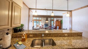 A kitchen with granite countertops, a double sink, and pendant lighting.