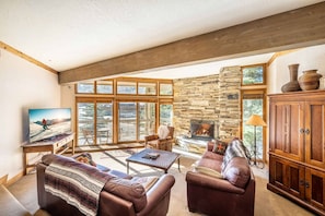 A cozy living room with a stone fireplace, leather sofas, and a television.