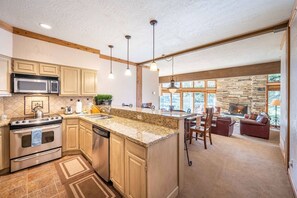 A spacious kitchen with granite countertops, wooden cabinets, and a central island.