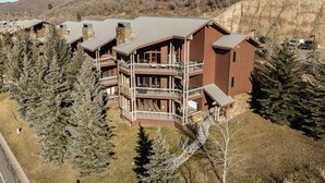 A multi-story lodge with a stone facade, multiple balconies, and a ski slope in the background.
