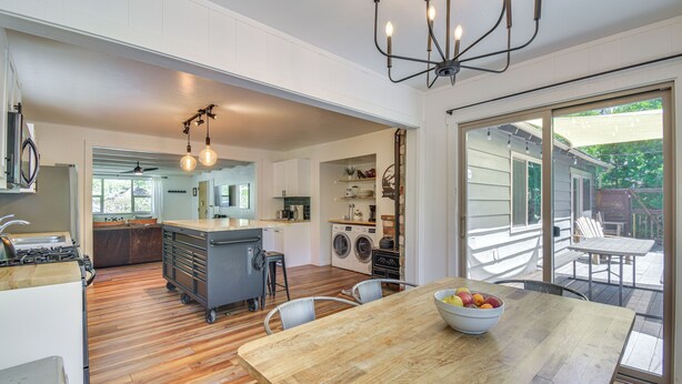 A modern kitchen with a wooden table and chairs, a fruit bowl, and a dining area with a view of the backyard. - Cozy Retreat w/ Deck ~ 2 Mi to Pinecrest Lake! (Strawberry)