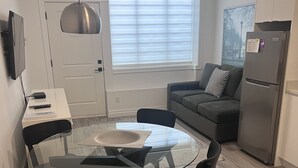 A modern kitchen with a round glass table, black chairs, a grey sofa, and a built-in fridge. - Amazing 1 Bedroom suite in Vancouver (Vancouver)