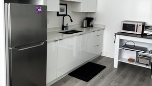A modern kitchen with white cabinets, a stainless steel refrigerator, a microwave, and a coffee maker. - Amazing 1 Bedroom suite in Vancouver (Vancouver)