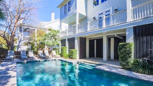 A pool area with lounge chairs and a two-story building with balconies. - 3 Min Walk to Beach! Serene Retreat w/ Heatable Private Pool, Ping Pong Table, Multiple Decks & Dens (Isle of Palms)