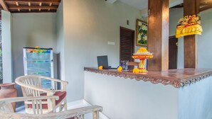 A room with a wooden chair, a small table, a refrigerator, and a decorative lamp. - D'Junas Villas by GenuineHost  (Ubud)