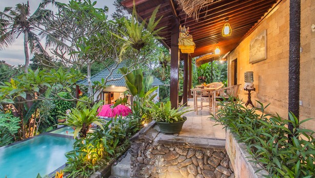 A tropical resort with a swimming pool, lush greenery, and a wooden pergola with hanging lights. - D'Junas Villas by GenuineHost  (Ubud)