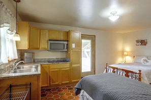 A compact kitchen with wooden cabinets, a built-in microwave, and a sink. - Nature Lover's Cottage on Wooded Acreage (Nova)