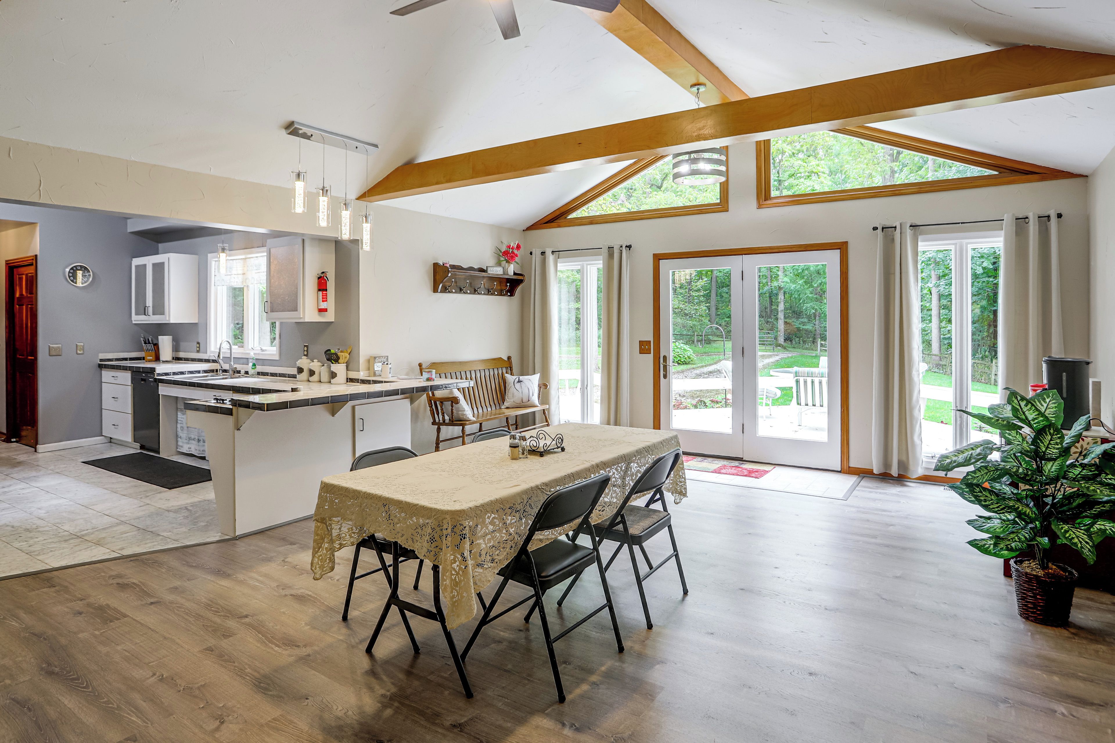 Une cuisine spacieuse avec un coin repas, des poutres apparentes et une grande porte-fenêtre coulissante donnant sur un jardin.