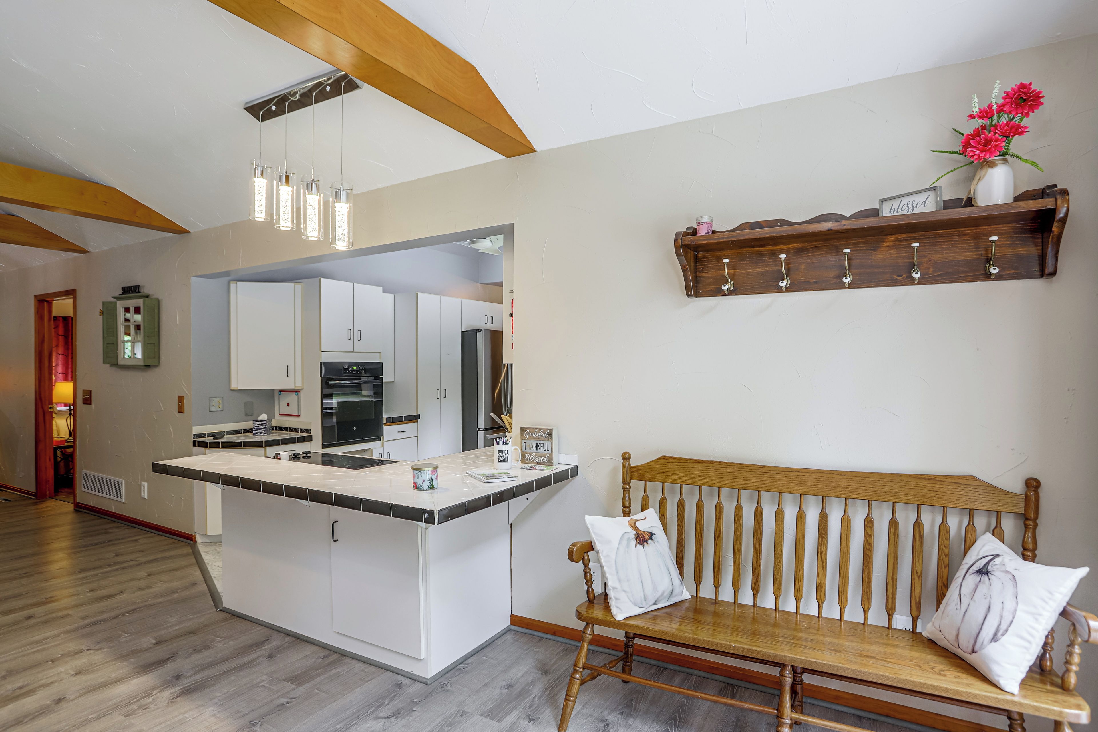 Una cocina moderna con una isla central, vigas de madera y un banco con cojines.
