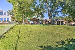 Zona residencial con césped cuidado, terraza de madera y un espacio de estar cubierto al aire libre.
