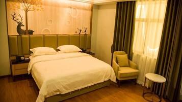 A hotel room with a large bed, a chair, a small table, and a decorative wall with a tree and animal silhouettes.