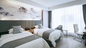 A hotel room with two beds, a large window with curtains, a desk with a chair, and a wall with a mountain painting. - Greentree Eastern Anshun Town Huangguoshu Avenue Jinhui Xindu Hotel (Anshun)