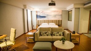 A modern hotel room with a bed, sofa, armchair, and a small table with a plant. - Greentree Eastern Anshun Town Huangguoshu Avenue Jinhui Xindu Hotel (Anshun)