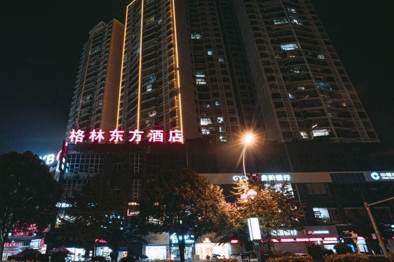 A high-rise hotel with illuminated signage, multiple floors, and surrounding commercial buildings.